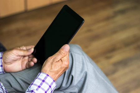 Senior man using modern digital tablet at home