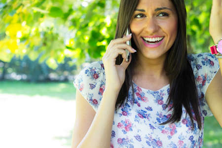 Woman enjoying the sun outdoors, using her smartphoneの写真素材