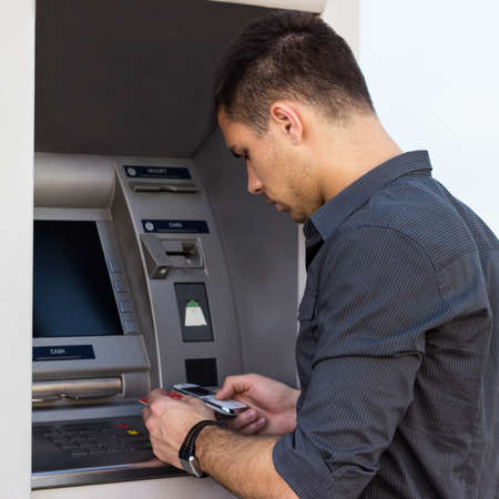 Young man put his credit card at the ATMの写真素材