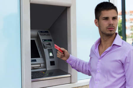 Young businessman withdrawing money from a cash machineの写真素材