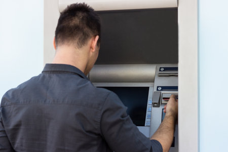 Young man put his credit card at the ATMの写真素材