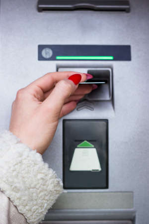 Woman using credit card to withdraw cash moneyの写真素材