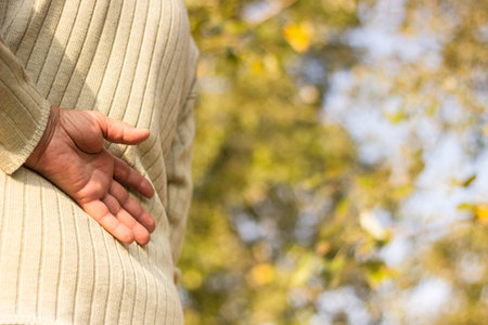 Senior woman with lower back pain. Nature bokeh background