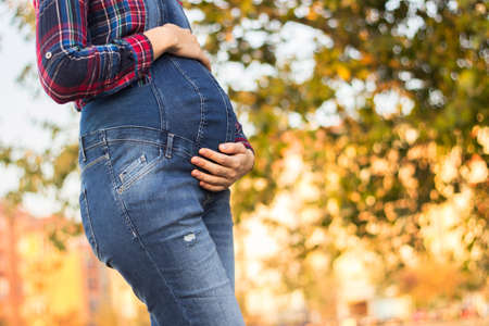 Beautiful pregnant woman touching her belly with handsの写真素材