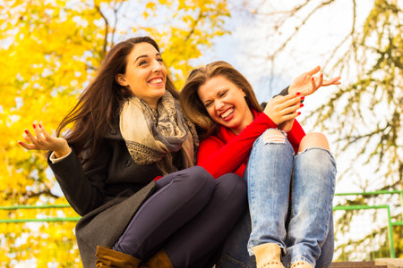 Two young smiling friends sitting on the stairs, portraitの写真素材