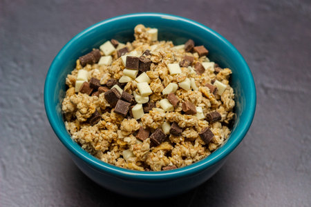 Sweet chocolate granola cereals in a blue bowl on a black background