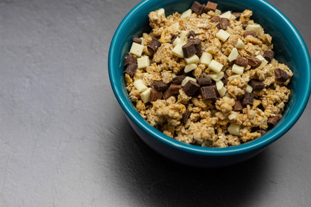 Sweet chocolate granola cereals in a blue bowl on a black backgroundの写真素材