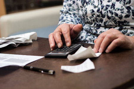 Senior woman checking her bills at home, sitting in her living roomの写真素材