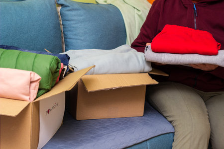 Woman holding clothes with Donate Box In her room. Gathering items to be donated to charityの写真素材