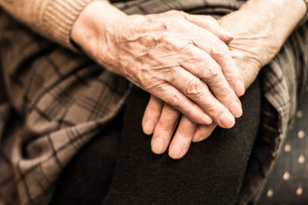 Grandmother's hands on the knee, sitting on the couchの写真素材