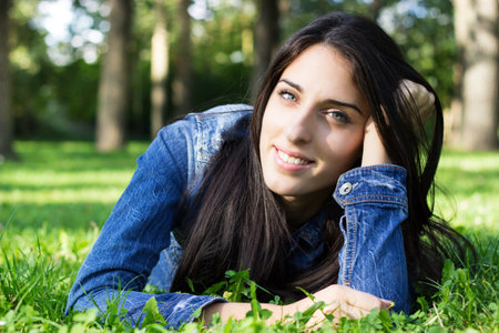 Beautiful young female lying on grass, looking at the camera. In the park.の写真素材