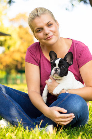 Smiling young woman playing with puppy. Her best friendの写真素材