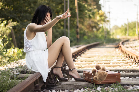 <p>Lonely and sad girl sitting on the railway and looking photos</p>の写真素材