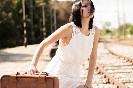 <p>Woman walking on railroad tracks with suitcase</p>の写真素材