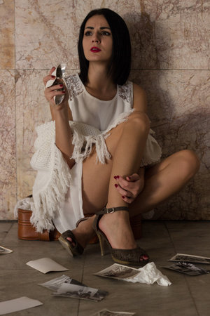 Beautiful girl sitting on a suitcase with a picture in hand and remember memoriesの写真素材
