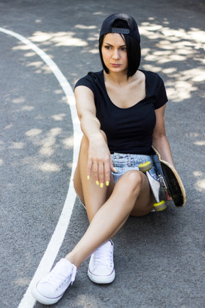 Teen girl with her skateboard , the basketball courtの写真素材