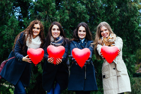 Four smiling women showing hearts, portraitの写真素材