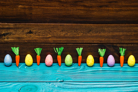 Easter eggs and carrots on empty wooden table with copy spaceの写真素材