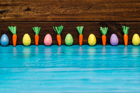 Easter eggs and carrots on empty wooden tableの写真素材