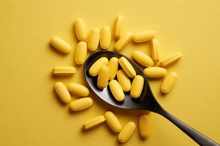Flat lay of pills or vitamins for immunity support on illuminating yellow background. Healthcare concept, nutritional supplements for healthy good life.の写真素材