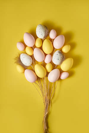 Creative Easter composition made with colorful eggs. Pink, yellow ad white Easter eggs designed as set of flying balloons on minimal yellow background. Holiday flat lay design.の写真素材