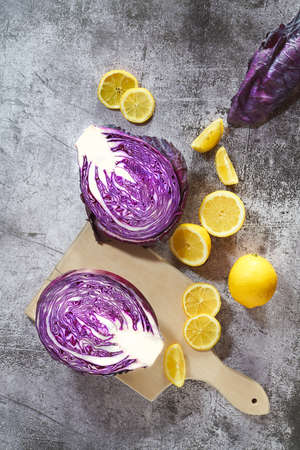 Overhead view of sliced raw red cabbage on cutting board with lemons. Kitchen colorful scene. Top view.の写真素材