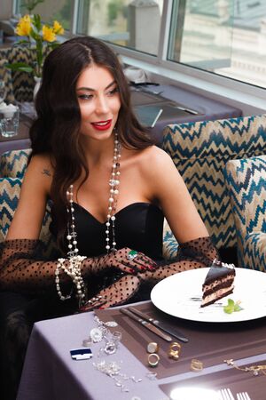 Girl at the table in gloves and jewelryの写真素材