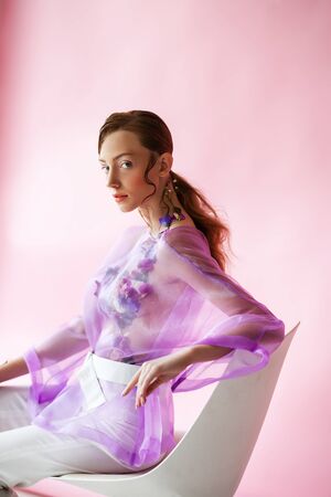 Beautiful brunette on a pink background. Decorated with flowersの写真素材