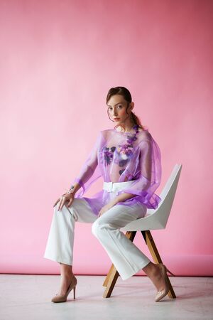 Beautiful brunette on a pink background. Decorated with flowersの写真素材