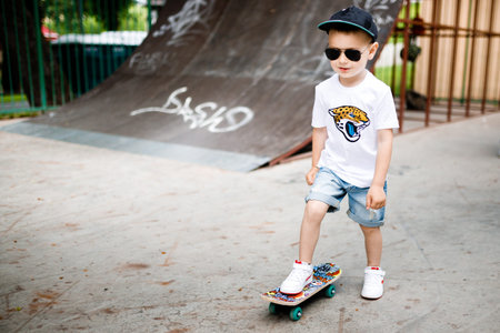 Boy with a skate in a skate park. A boy with glasses learns to skate.
