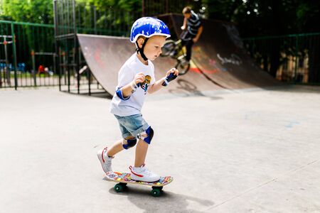 Boy with a skate in a skate park. The boy learns to skate, in full protection.の写真素材