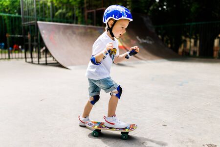 Boy with a skate in a skate park. The boy learns to skate, in full protection.の写真素材