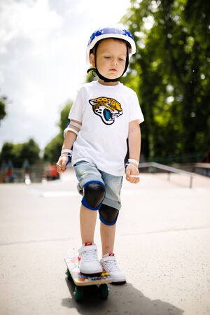 Boy with a skate in a skate park. The boy learns to skate, in full protection.の写真素材