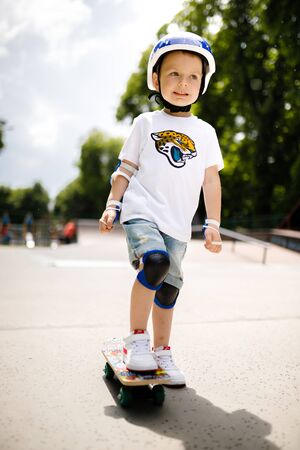 Boy with a skate in a skate park. The boy learns to skate, in full protection.の写真素材