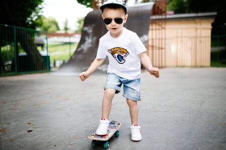 Boy with a skate in a skate park. A boy with glasses learns to skate.の写真素材