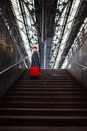 Railway station. Beautiful girl waiting for the train. Woman travels the world. Lady in a red cap and with a red bag, urban geometry.の写真素材