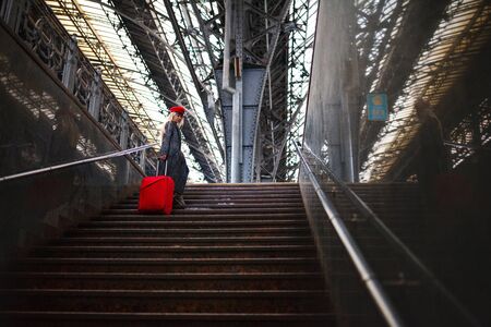 Railway station. Beautiful girl climbs the stairs. Lady in a red cap.の写真素材