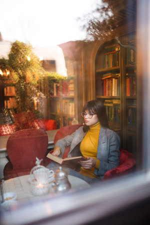 Beautiful dreamy girl in stylish sharp glasses. In the library.