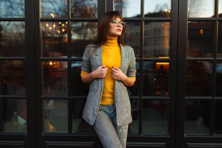 Beautiful dreamy girl in stylish sharp glasses. Near the shop windowの写真素材