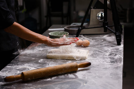 The chef prepares pastries in a professional kitchen. Dark background.