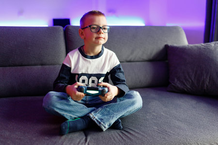 Boy Danya in glasses plays on a game console.