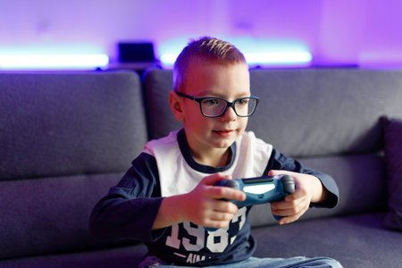Boy Danya in glasses plays on a game console.