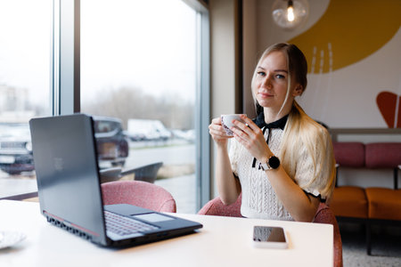 A girl works at a computer in a coffee shop.の写真素材