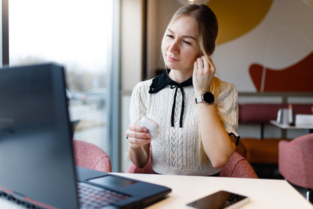A girl works at a computer in a coffee shop.の写真素材