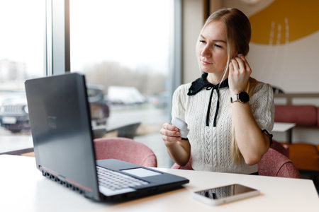 A girl works at a computer in a coffee shop.の写真素材