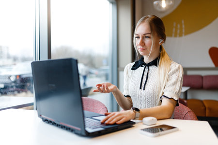 A girl works at a computer in a coffee shop.の写真素材