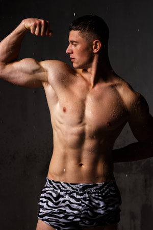 Athlete bodybuilder trains in the studio in the rain.の写真素材