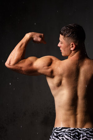 Athlete bodybuilder trains in the studio in the rain.の写真素材