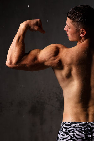 Athlete bodybuilder trains in the studio in the rain.の写真素材