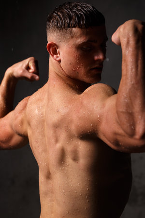 Athlete bodybuilder trains in the studio in the rain.の写真素材